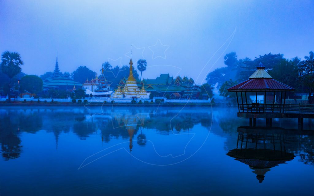 Goldener thailändischer Tempel und Pavillon spiegeln sich zur blauen Stunde in einem nebligen See, Seeuferszene wie in Mae Hong Son