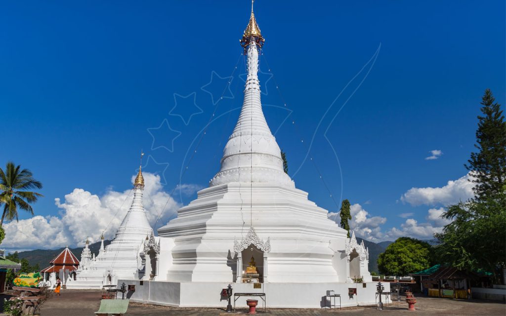 Weiße buddhistische Chedis mit goldenen Spitzen im Hügeltempel Wat Phra That Doi Kong Mu unter blauem Himmel, Thailand