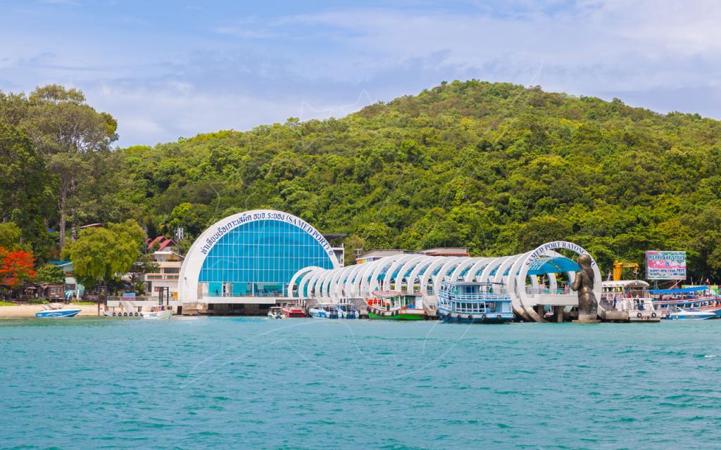 Jetée du port de Samet à Rayong, Thaïlande : passerelle blanche en arches, ferries amarrés et mer turquoise sous une colline verte