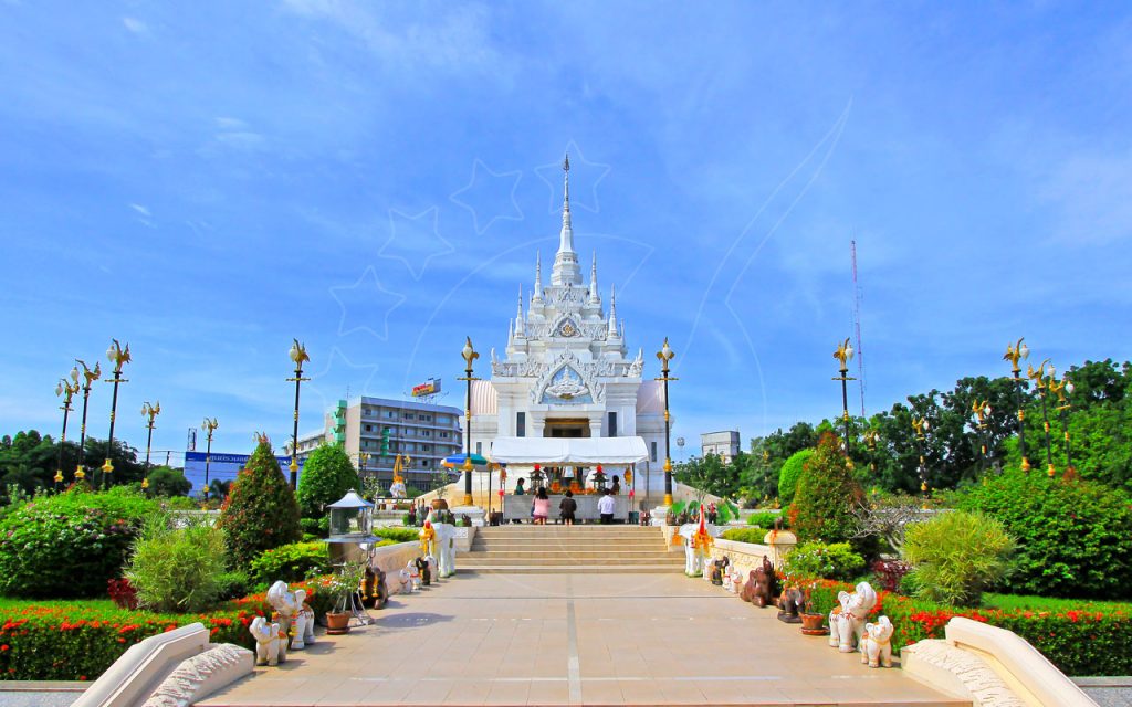 Elaborato santuario bianco del pilastro della città thailandese con guglie, statue di elefanti e giardini curati sotto il cielo azzurro