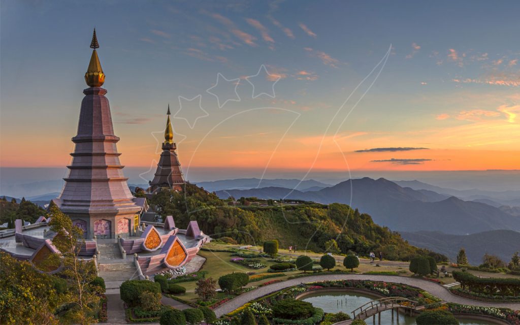 Due pagode reali con guglie dorate su un crinale del Doi Inthanon, Thailandia, sopra colline nebbiose al tramonto