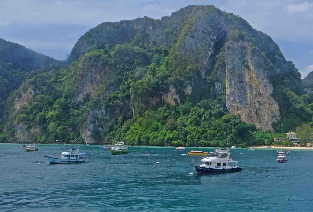 Türkisfarbene Bucht mit vertäuten Fischerbooten und Kalksteinfelsen voller grüner Vegetation